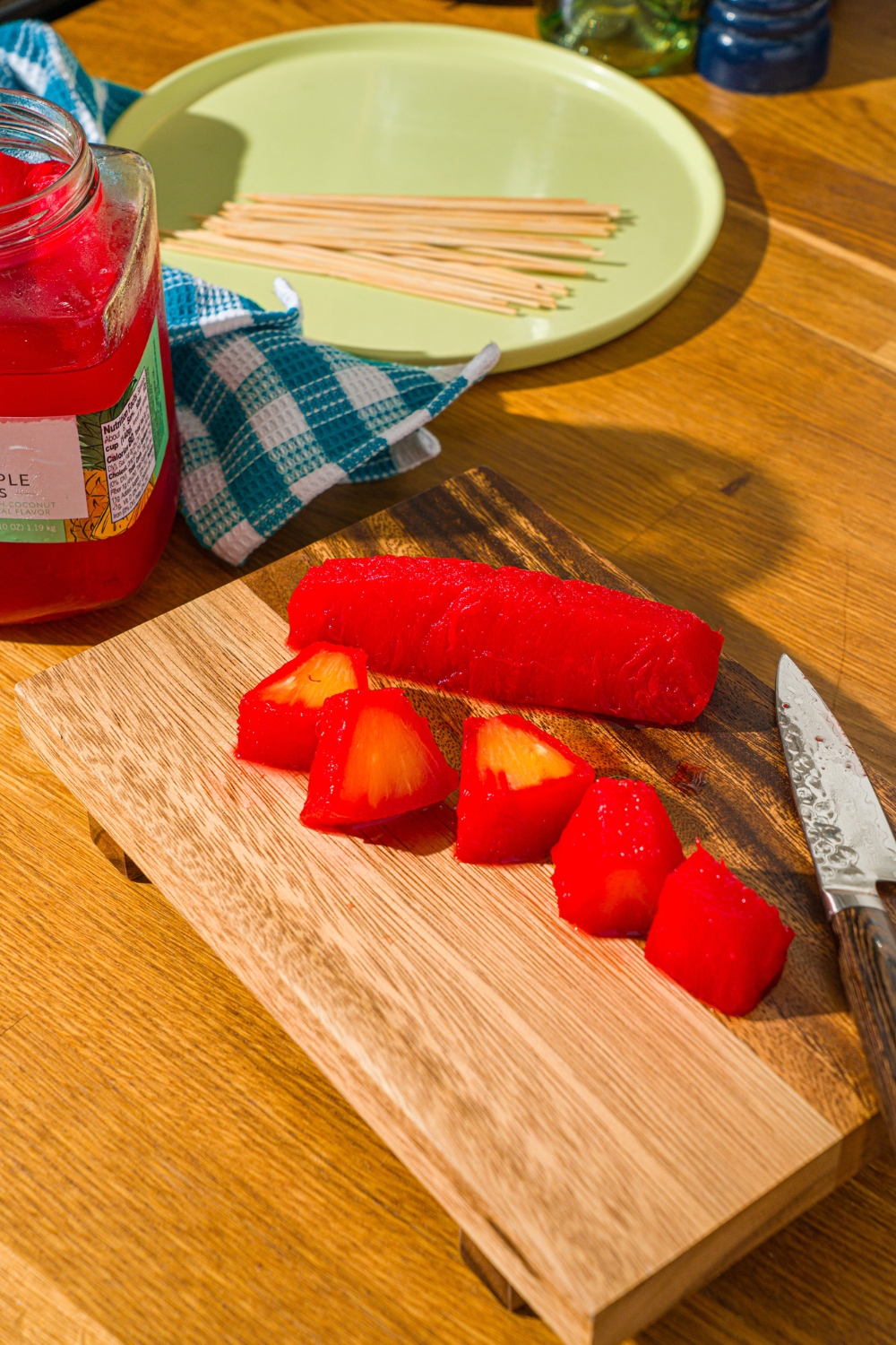 A Kool-Aid pineapple spear and a sliced Kool-Aid pineapple spear on a wooden cutting board.