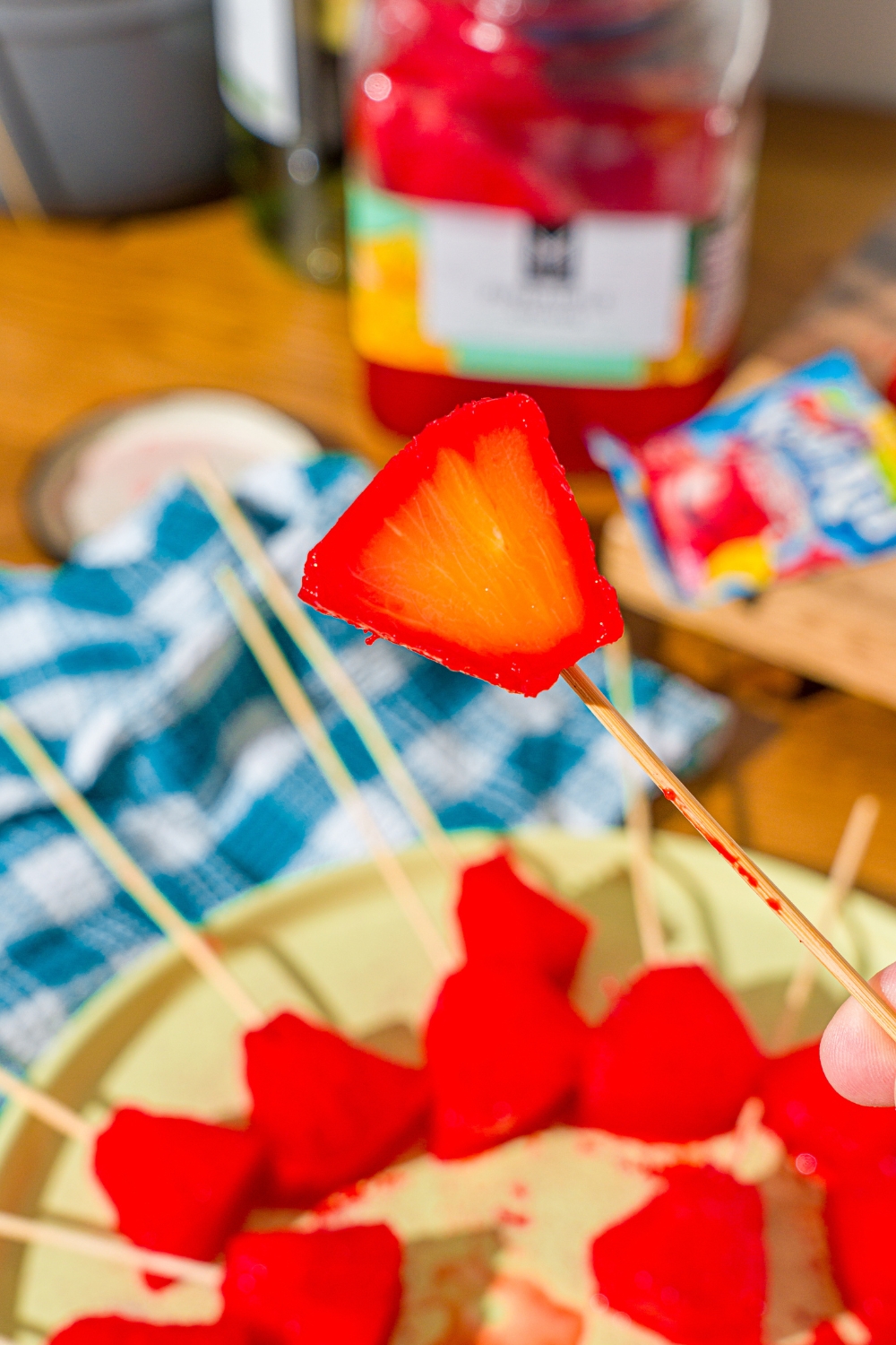 A hand holding a Kool-Aid pineapple spear piece that is on a toothpick.