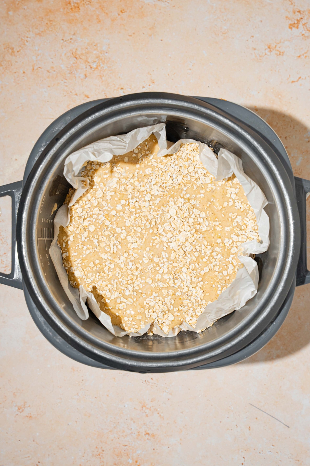 Dry oats on top of banana bread, batter on parchment paper that is in a rice cooker.