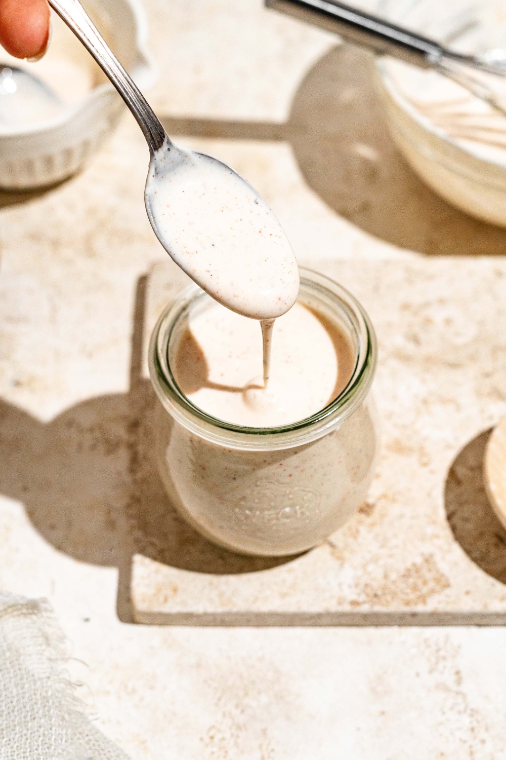 A small jar with Outback ranch dressing on a tan counter. A spoon is dipping into the jar.