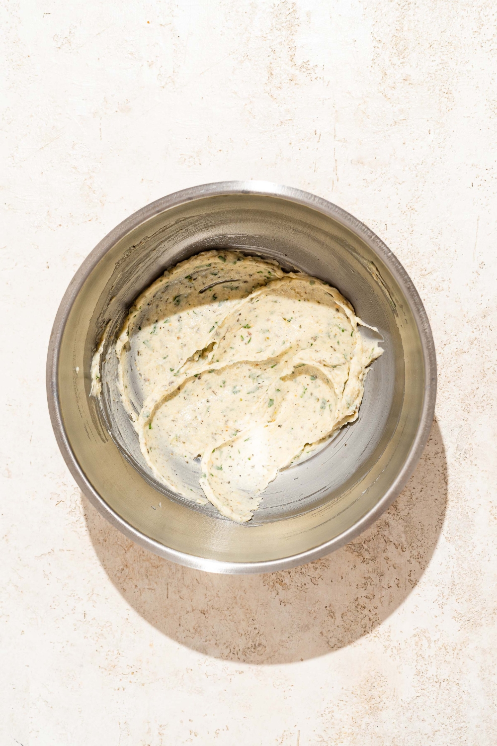 A large bowl with a garlic butter mixture. The bowl is on a tan counter.