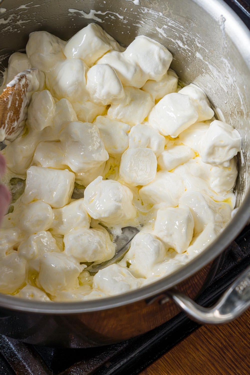 A large pot with marshmallows cooking in butter on a stove.