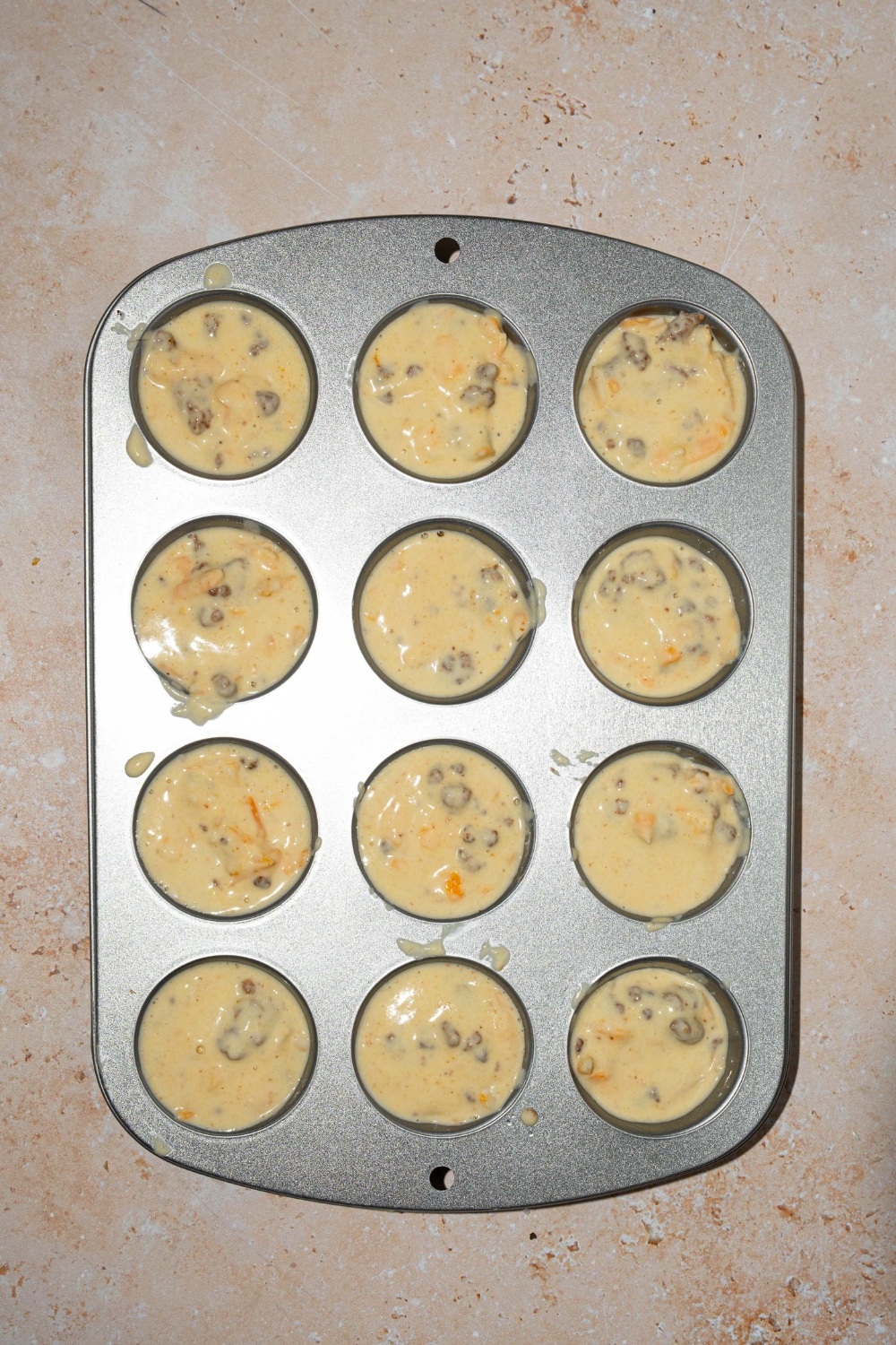 A mini muffin tin filled with McGriddle muffin batter. The tin is on a tan counter.