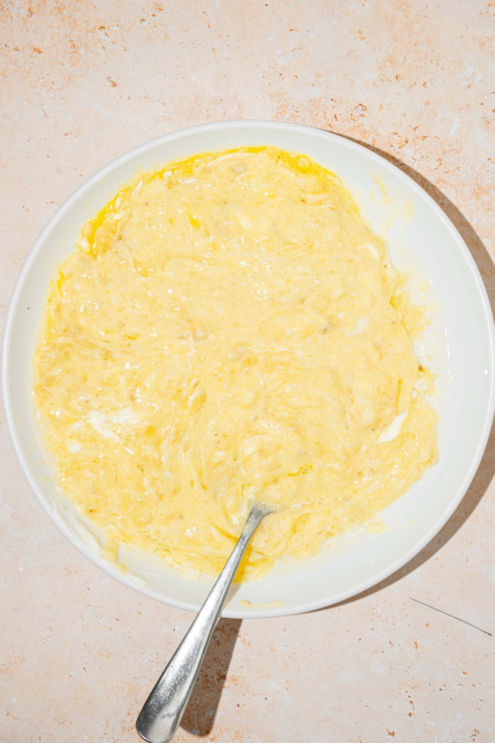 A mashed banana mixture on a white plate for rice cooker banana bread.