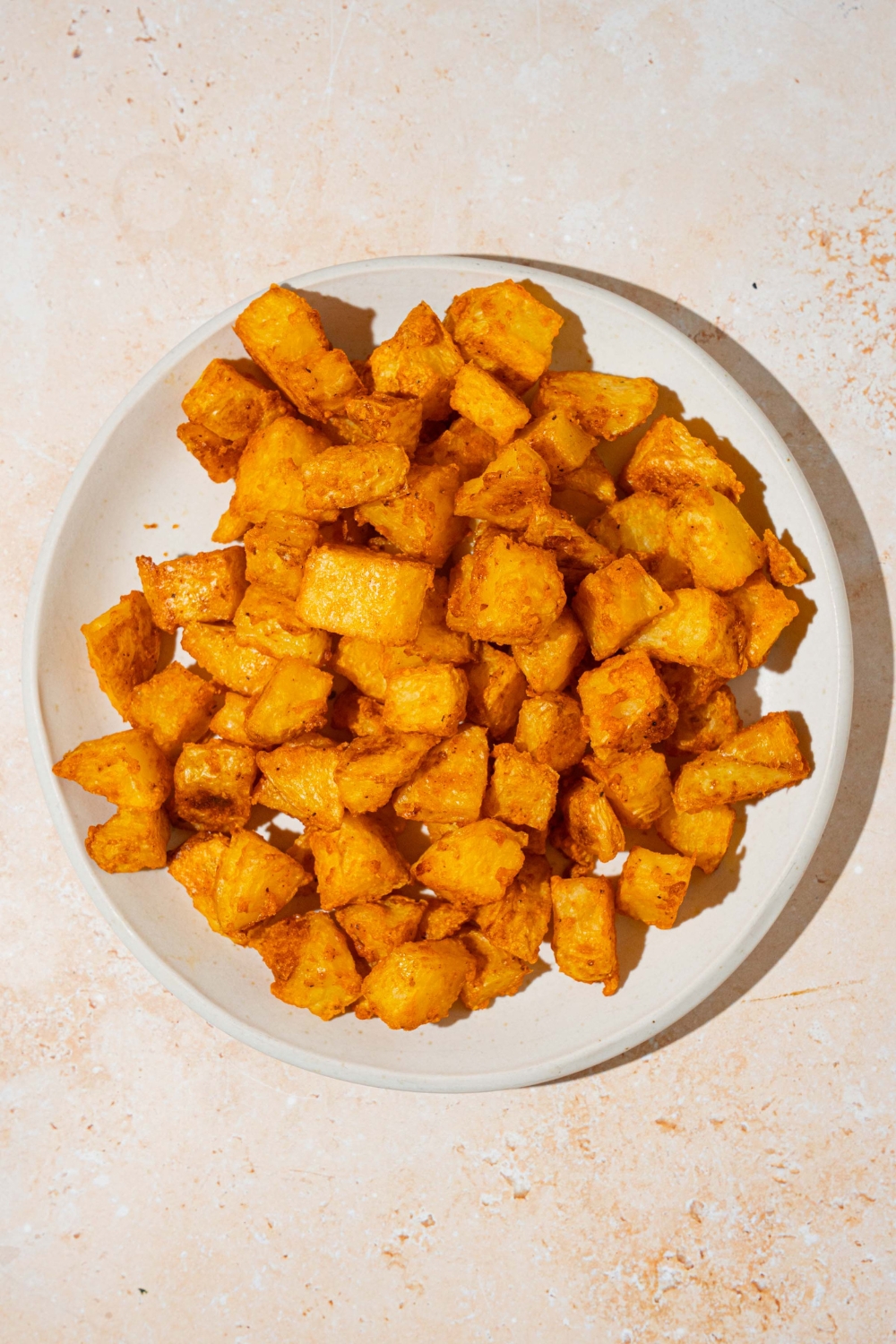 A white plate with baked fiesta potatoes. The plate is on a tan counter.