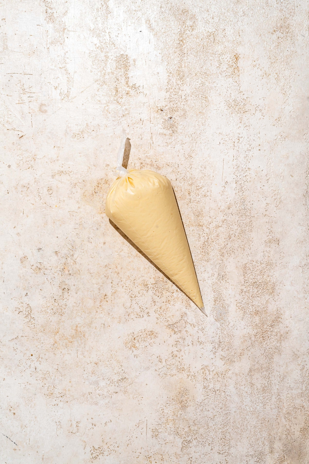 A piping bag with funnel cake batter. The bag is on a tan counter.