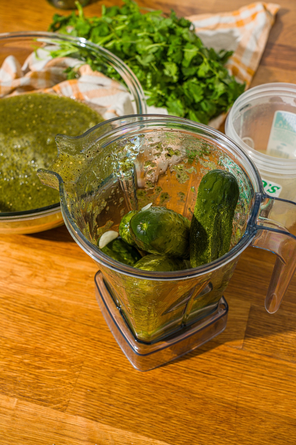 A blender with drained Grillo's pickles. The blender is on a wooden counter with a glass bowl of a vegetable salsa base.