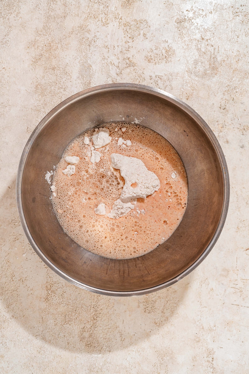 A large bowl with a wet batter mixture. The bowl is on a tan counter.