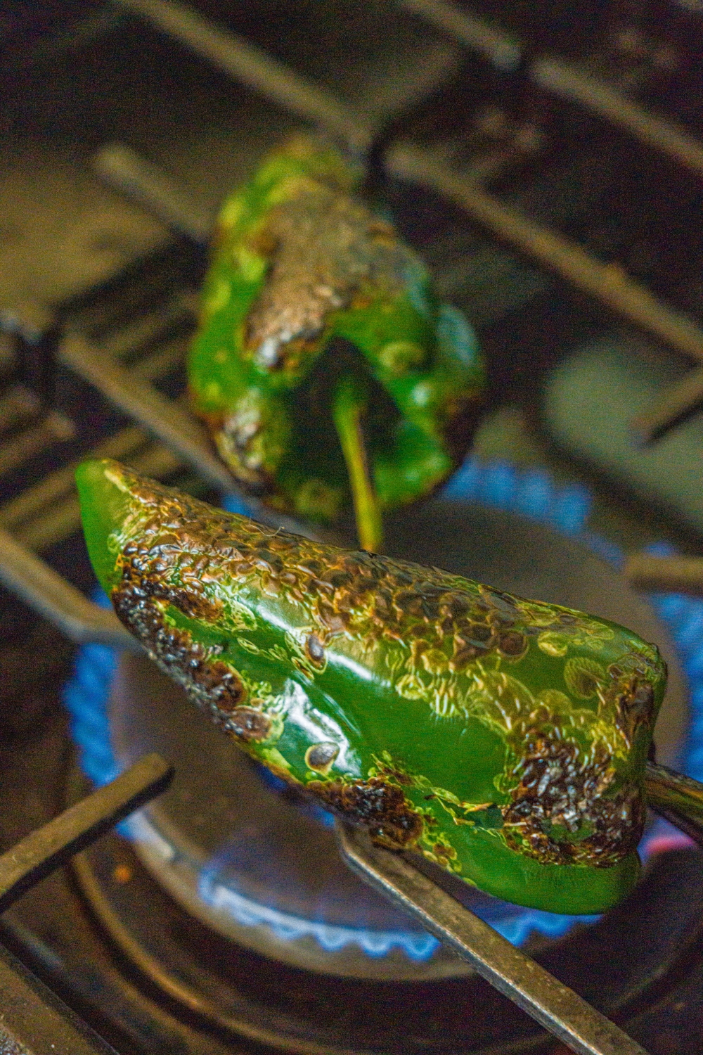 A stove with poblano peppers charring on the fire.