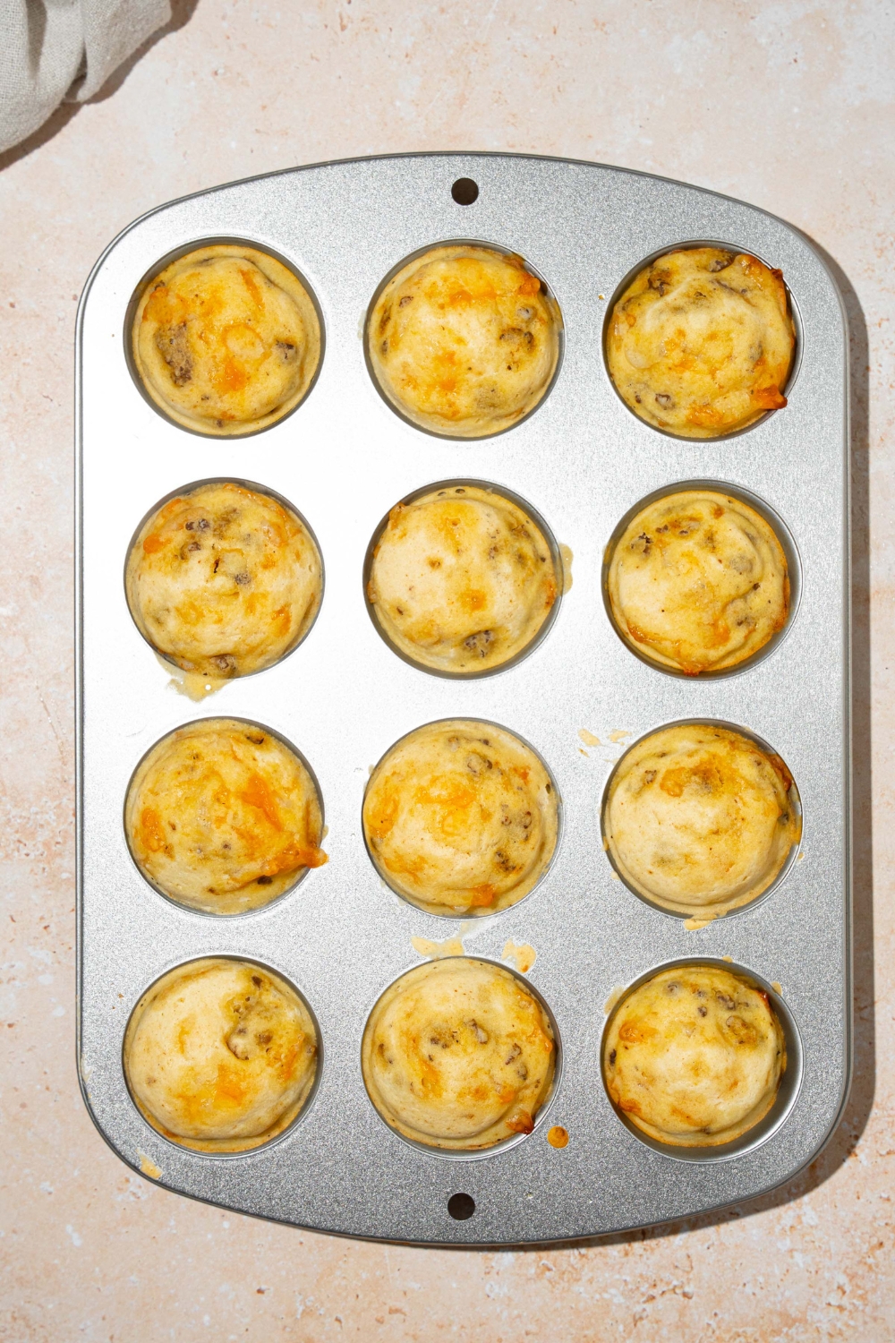 A mini muffin tin with baked McGriddle muffins. The tin is on a tan counter.