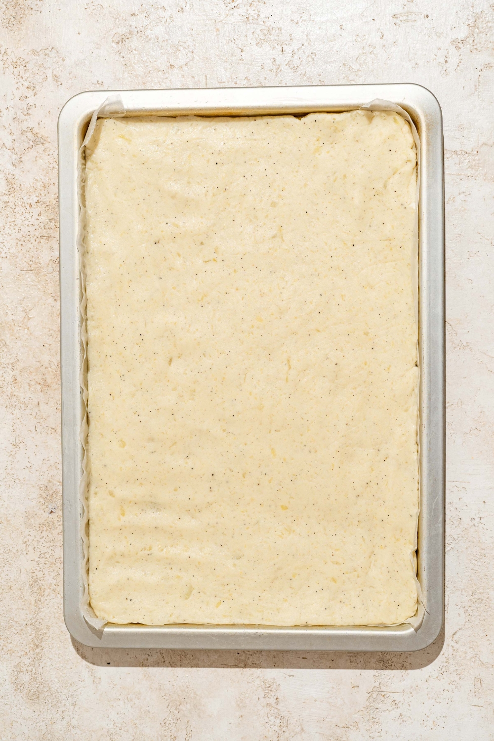A baking sheet with chilled, rectangular Japanese long fry dough. The sheet is on a tan counter.