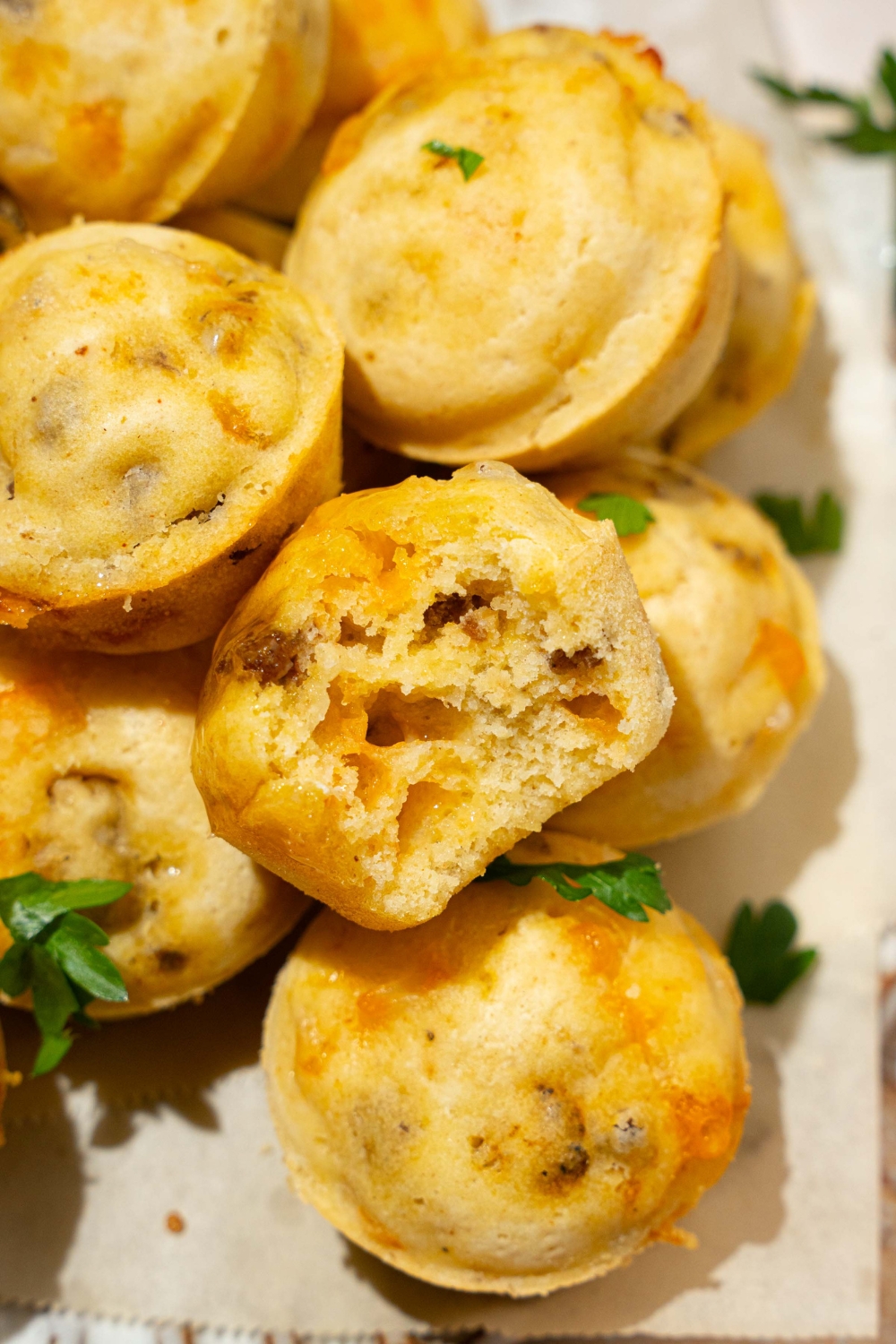 A pile of McGriddle muffins garnished with fresh parsley. One of the muffins has a bite taken from it.