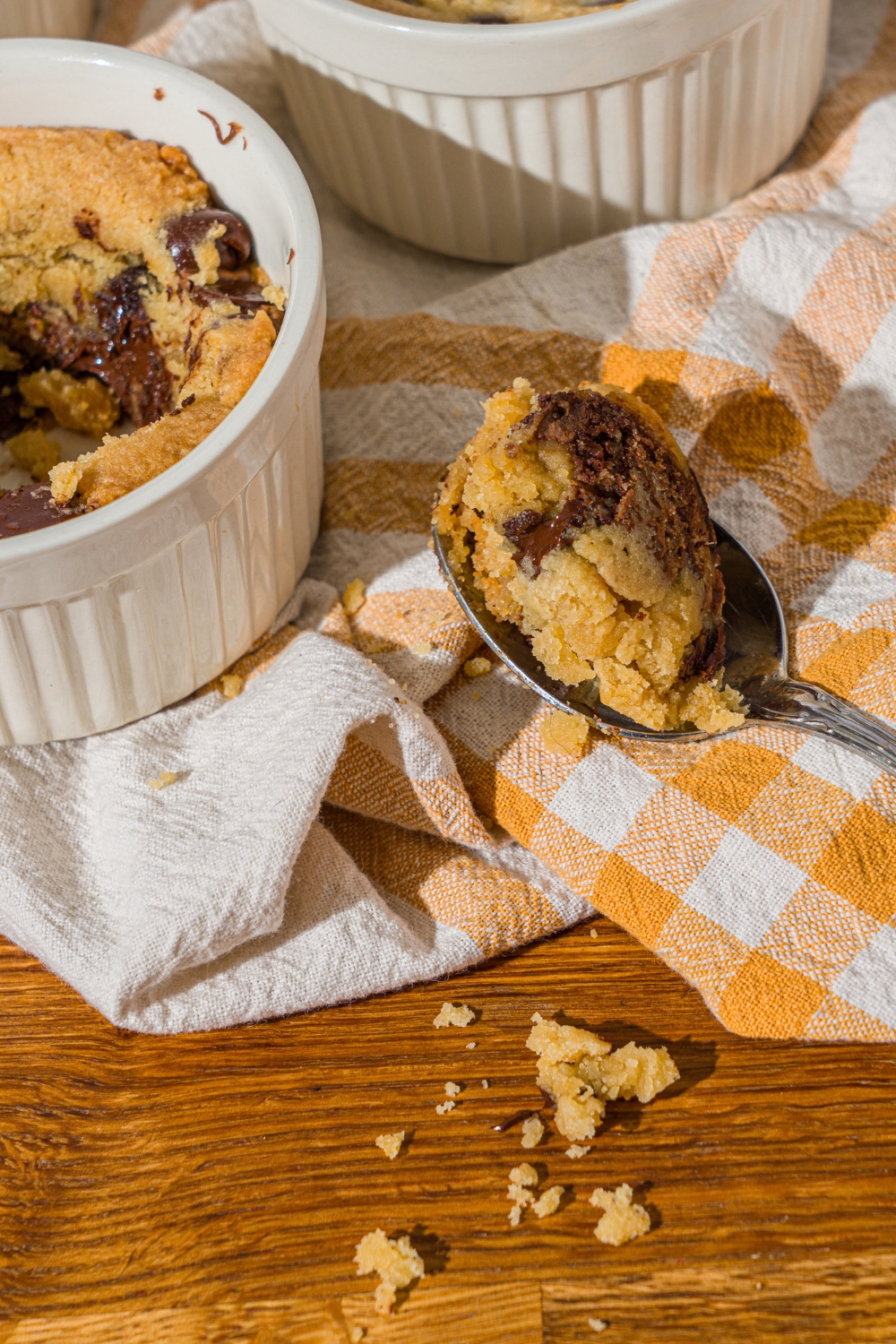 A spoon with a bite of nutella cookie pie on a wooden counter with a yellow striped napkin.
