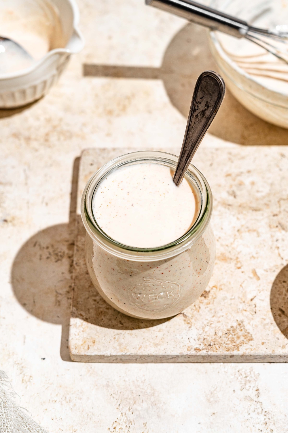 A jar with Outback ranch dressing on a tan counter. There is a spoon in the jar.