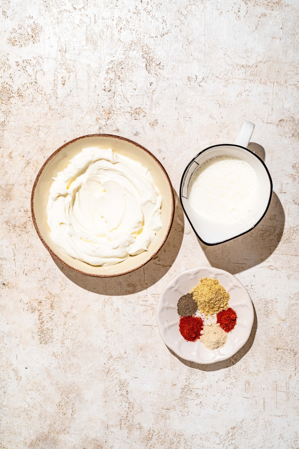 A tan counter with ingredients to make Outback ranch dressing including mayo, buttermilk, and seasonings.