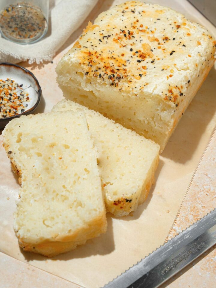A loaf of blender rice bread with two slices of the bread in cut and laying on top of each other in front of it.