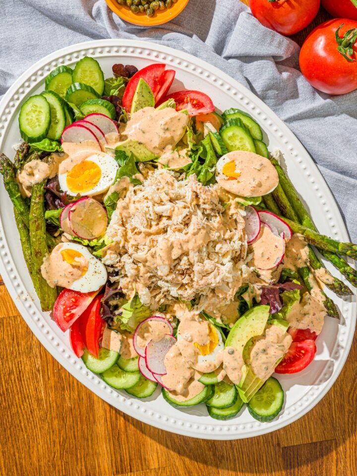 Louie dressing on top of a Louie salad spread out over a white serving platter.