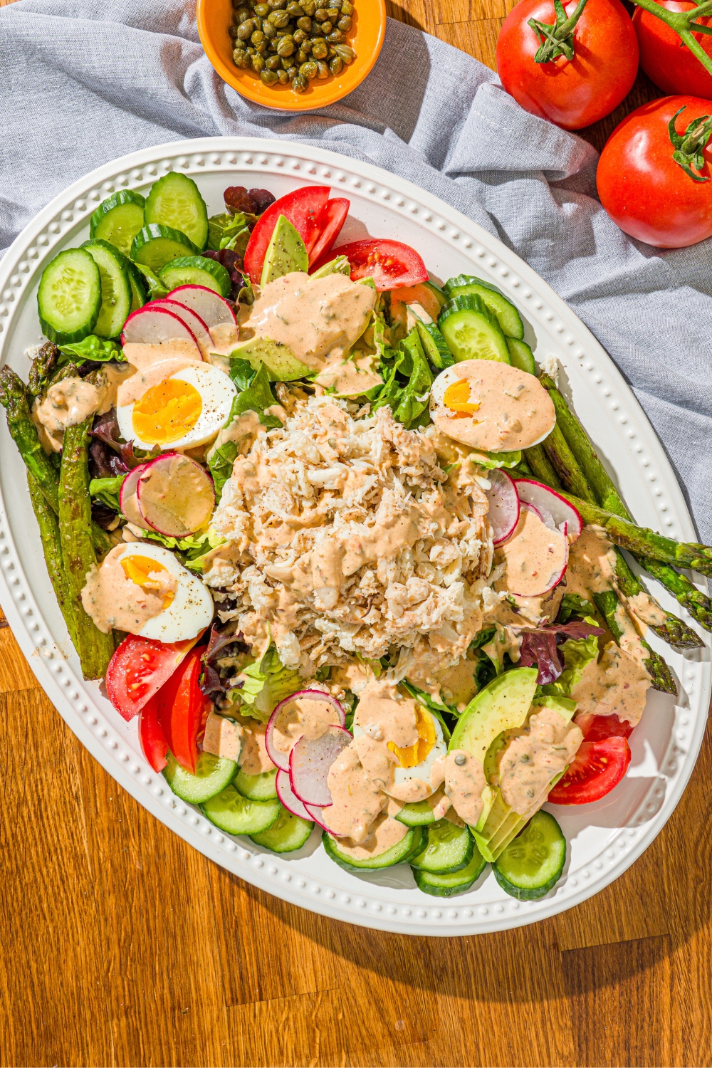Louie dressing on top of a Louie salad spread out over a white serving platter.