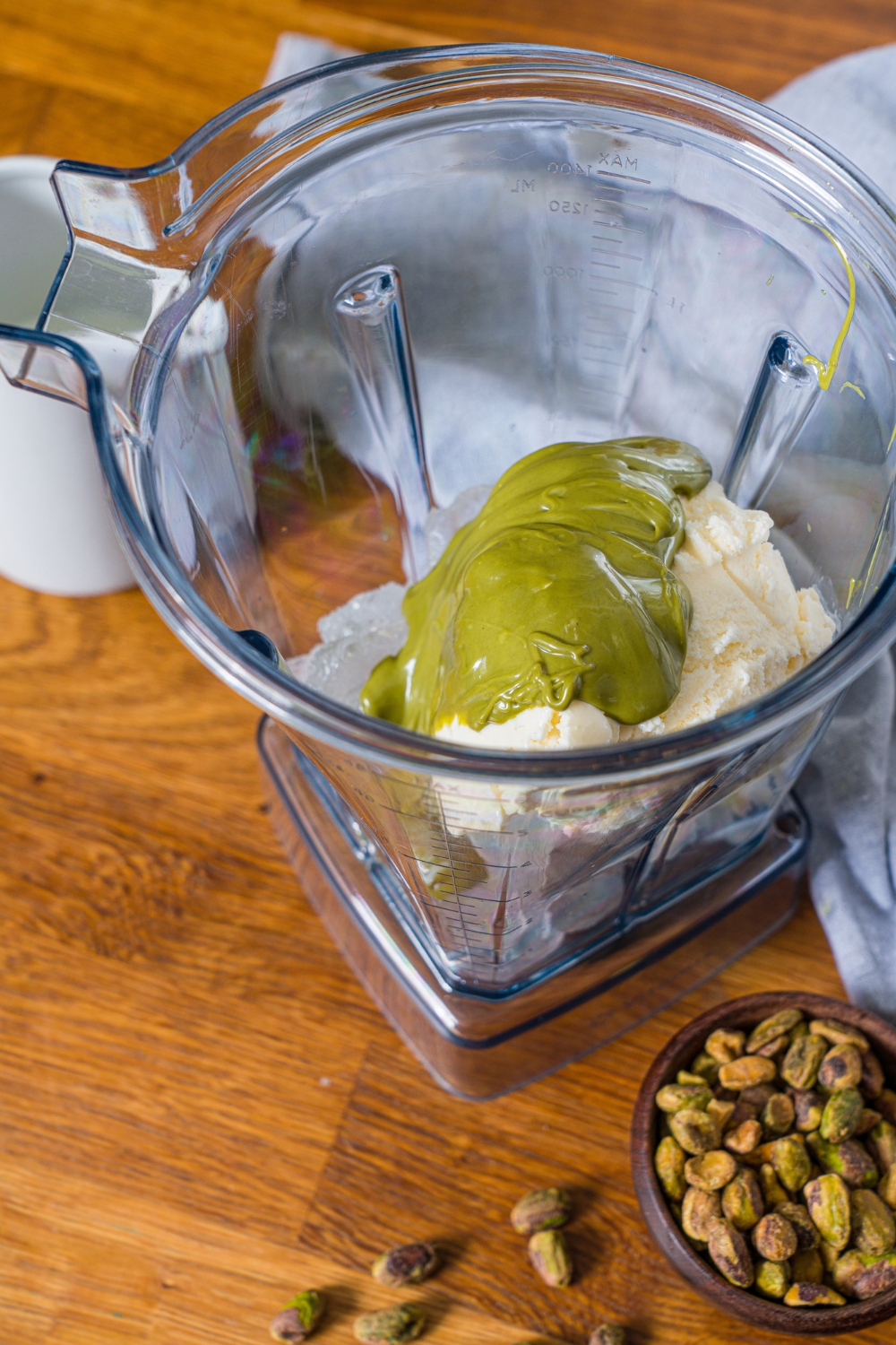 A blender that has pistachio cream, and vanilla ice cream in it.