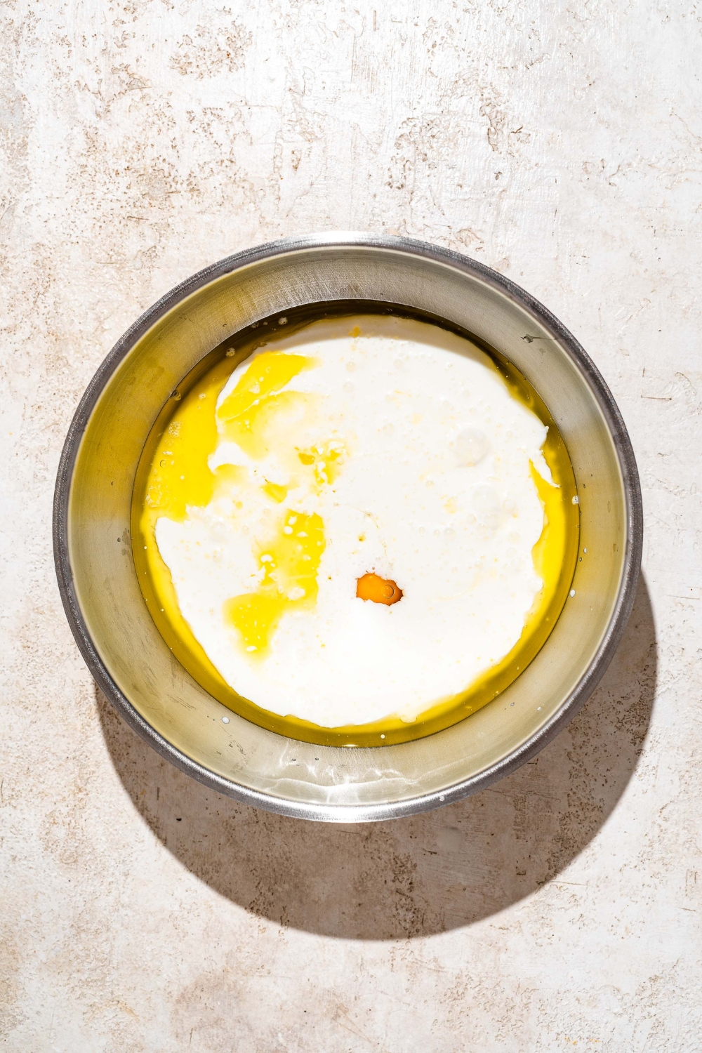 A stainless steel bowl that has buttermilk and melted butter in it for golden diner pancakes.