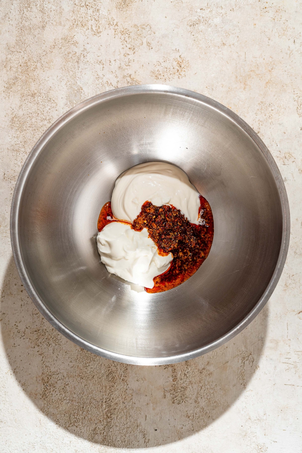 A metal bowl filled with yogurt, heavy cream, and a butter spice mixture.