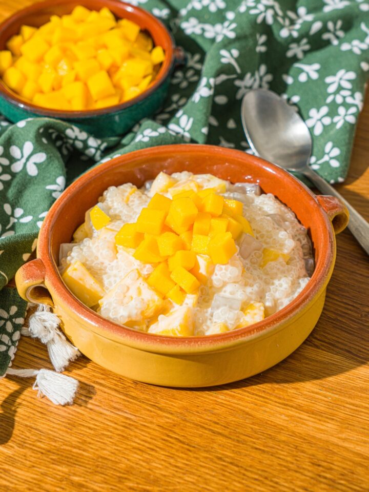 Mango sago in a bowl with diced mango on top. Behind it is a bowl with diced mangos in it.