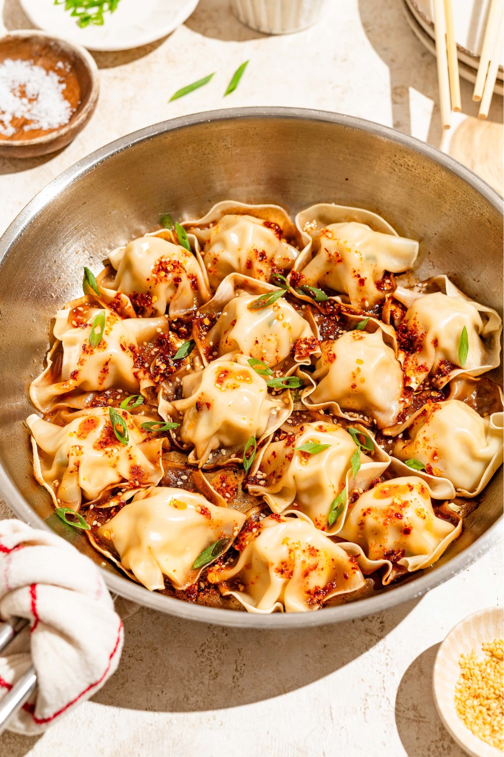 A bunch of no fold blanket dumplings in a stainless steel skillet.