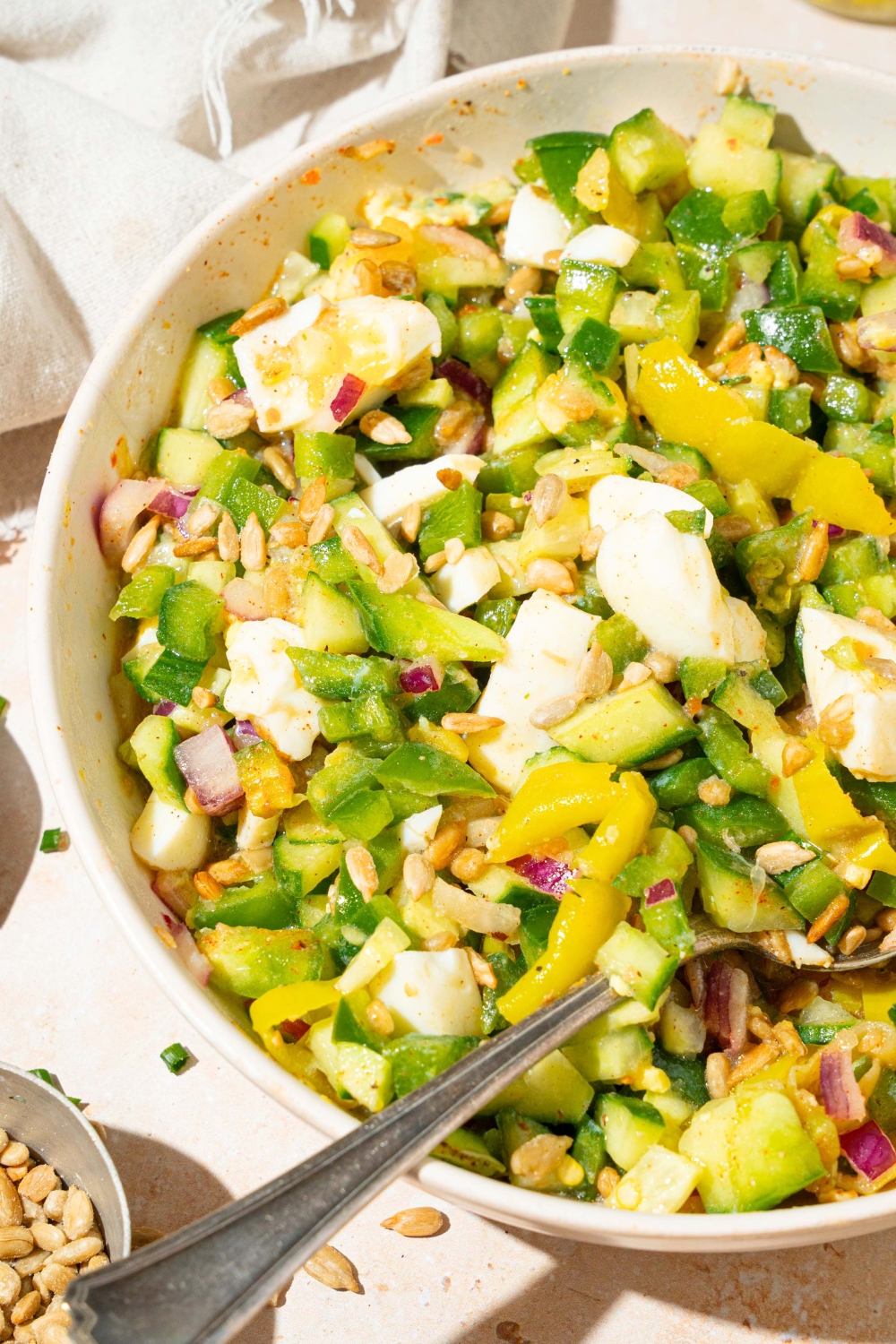 Part of a white bowl that has a hot girl summer salad in it.