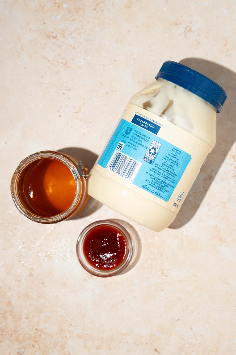 A tan counter with ingredients for honey sriracha sauce including mayo, honey, and sriracha.
