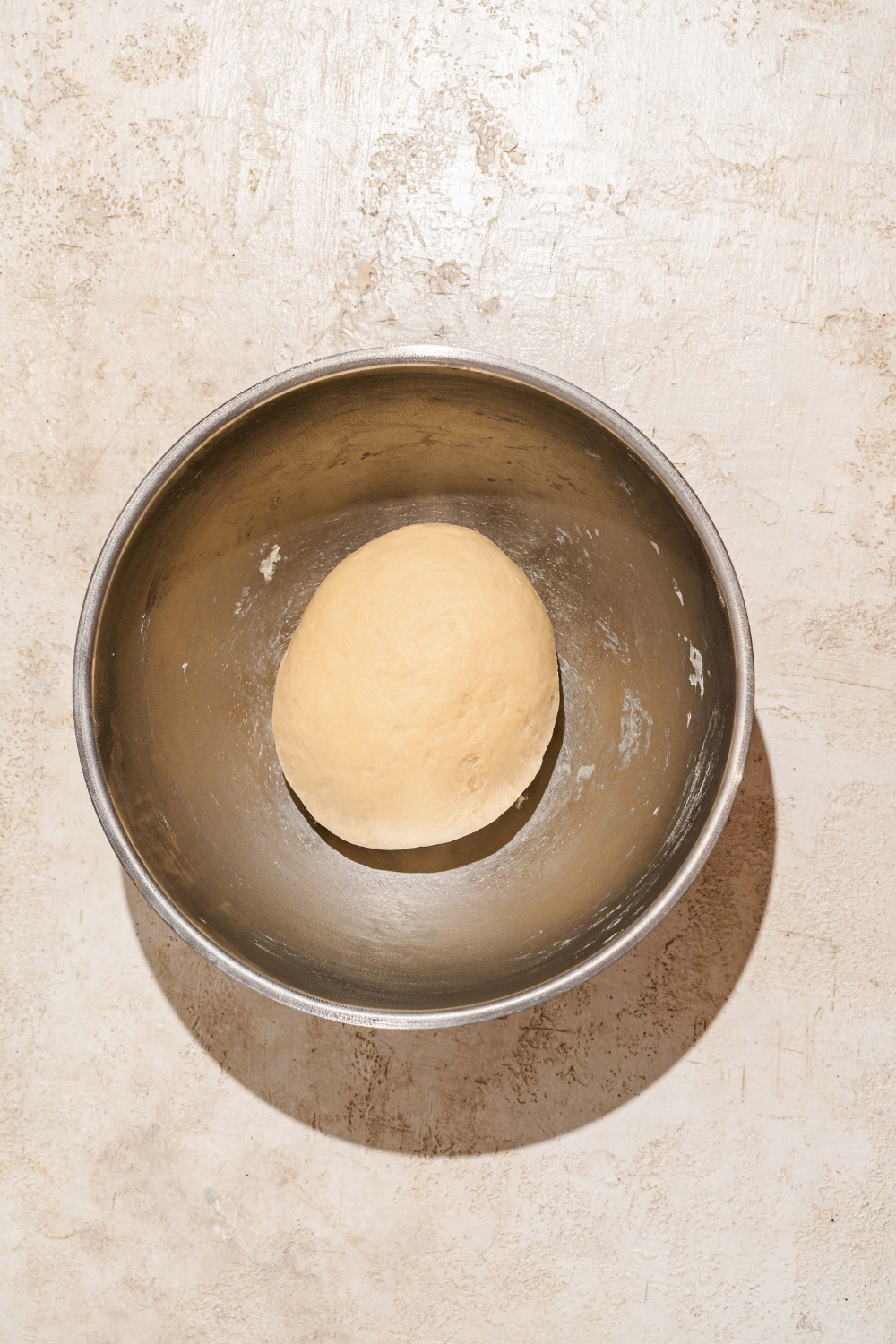 A large bowl with a Raising Cane's bread dough ball. The bowl is on a tan counter.