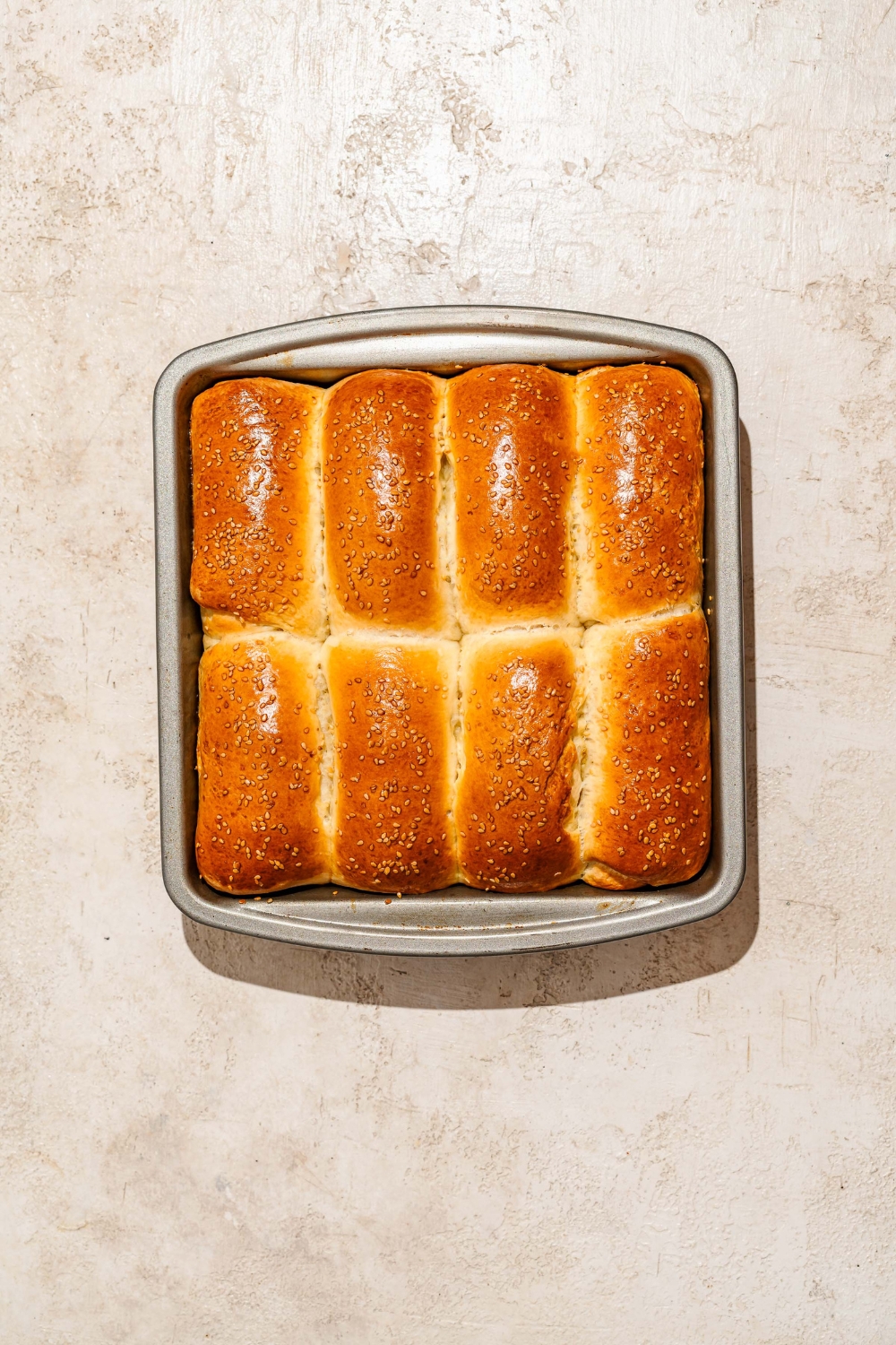 A large loaf pan with several baked pieces of Raising Cane's bread. The pan is on a tan counter.