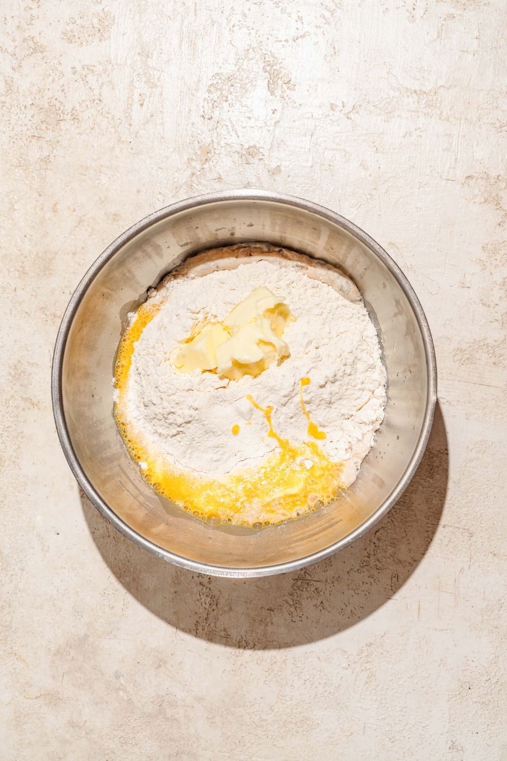 A large bowl with Raising Cane's bread dough ingredients added to a yeast mixture. The bowl is on a tan counter.