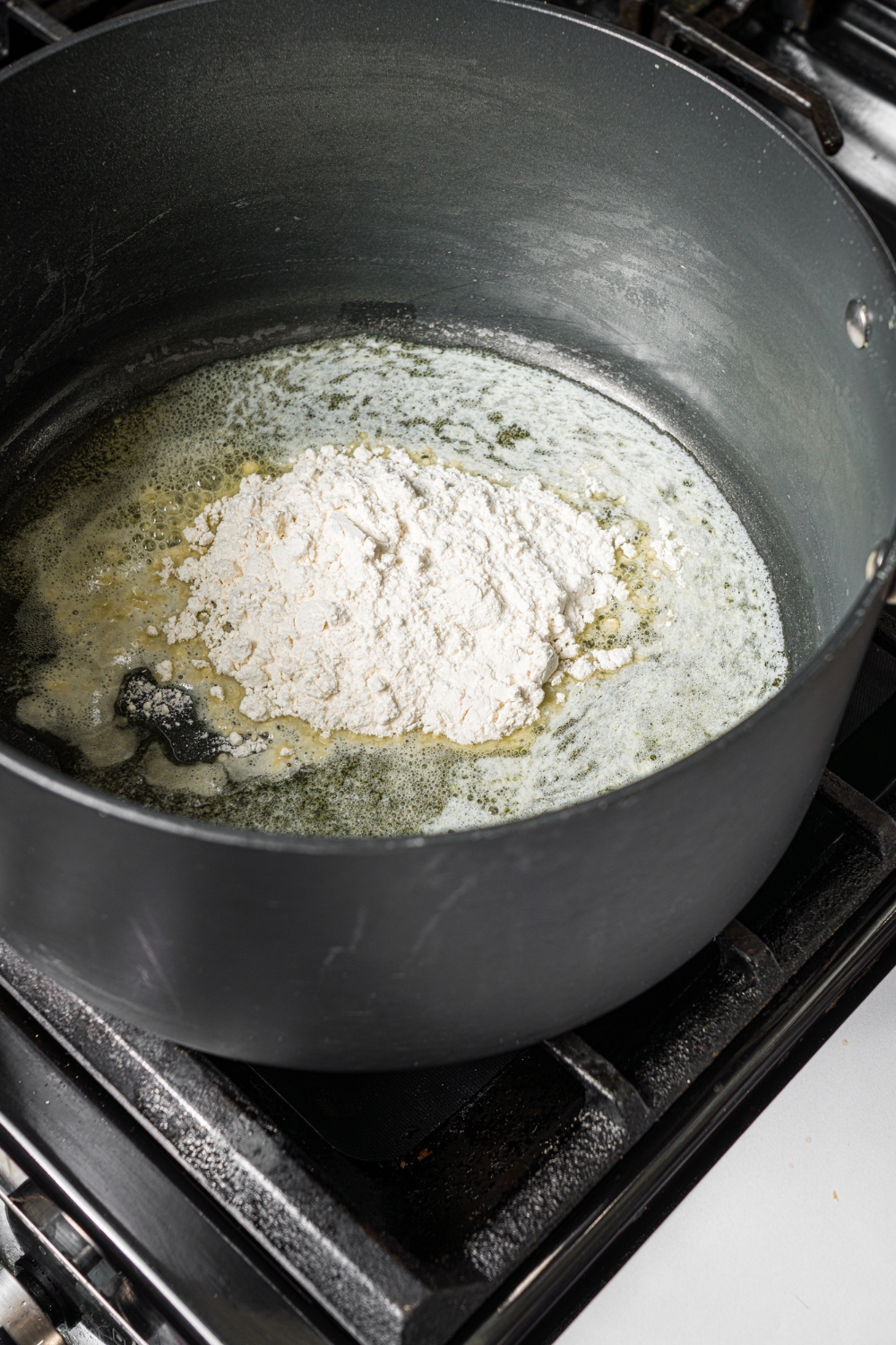 A large pot with flour cooking in butter to make a roux. The pot is cooking on a stove.