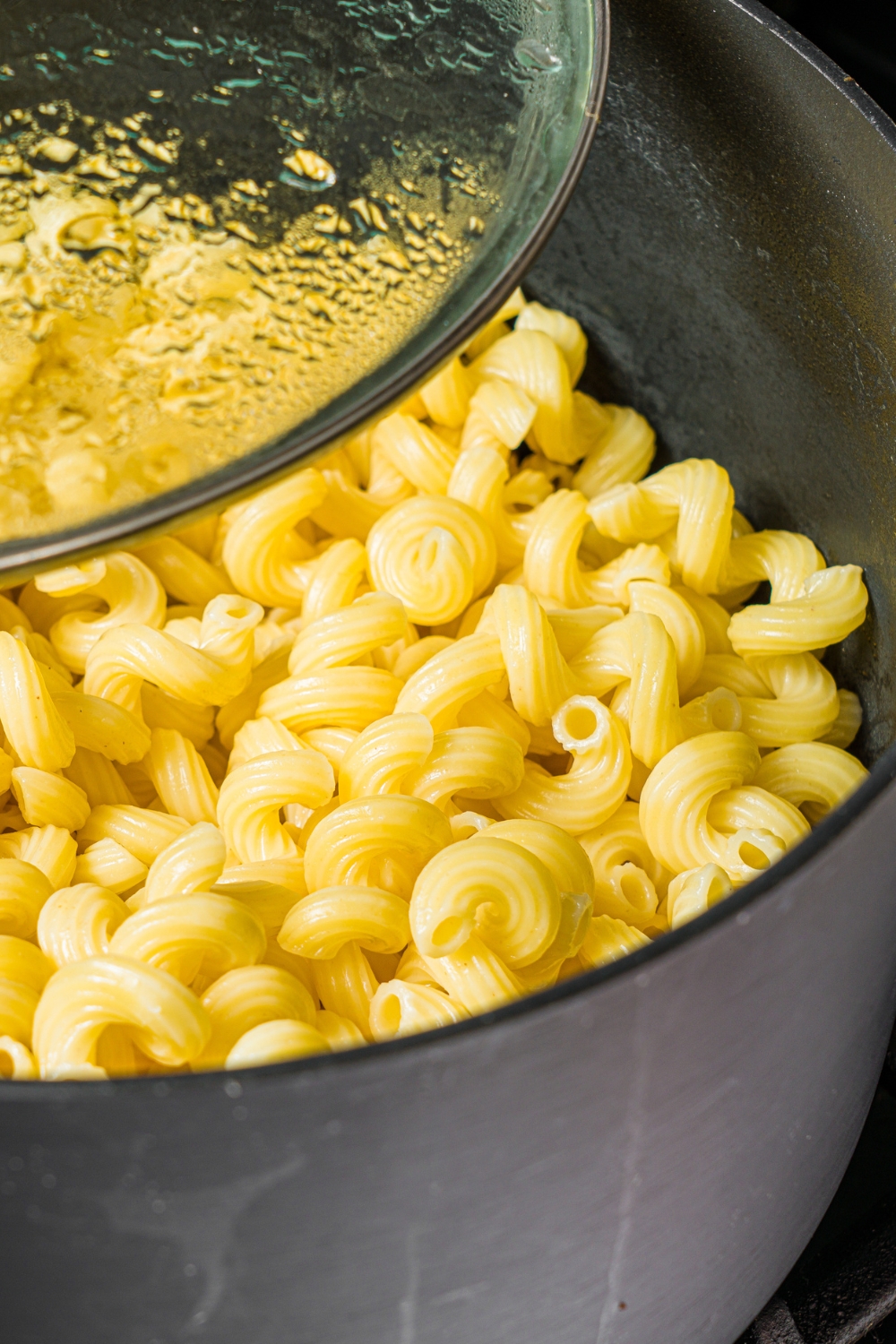 A large pot with cooked cavatappi pasta.