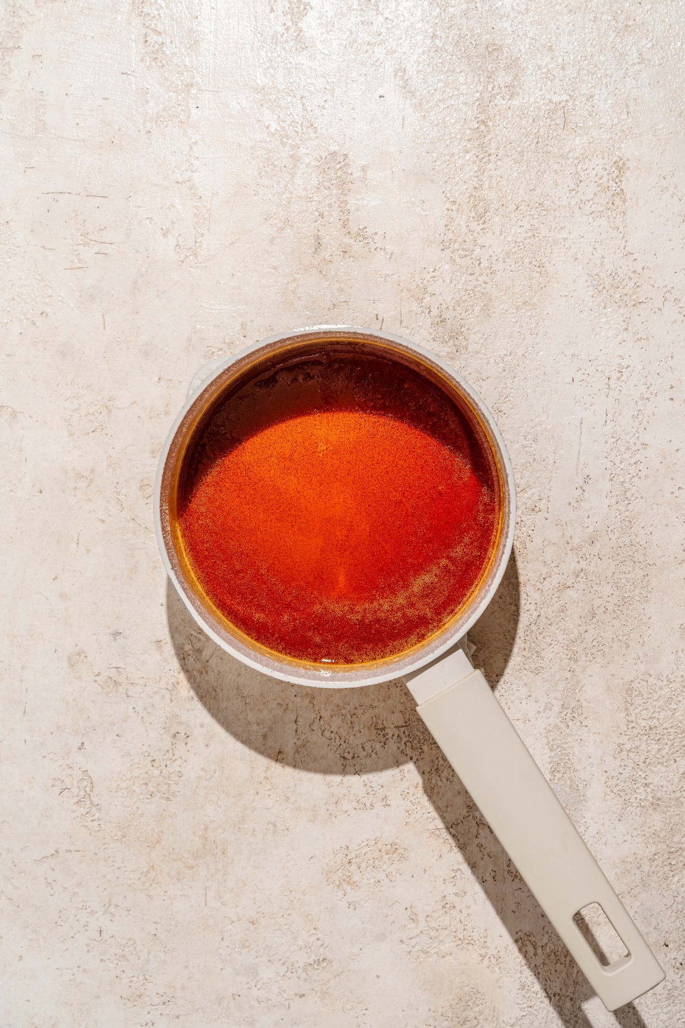 A saucepan with cooked caramel. The saucepan is on a tan counter.