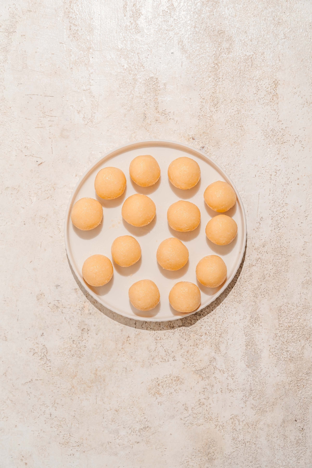 A plate with bala baiana dough balls. The plate is on a tan counter.