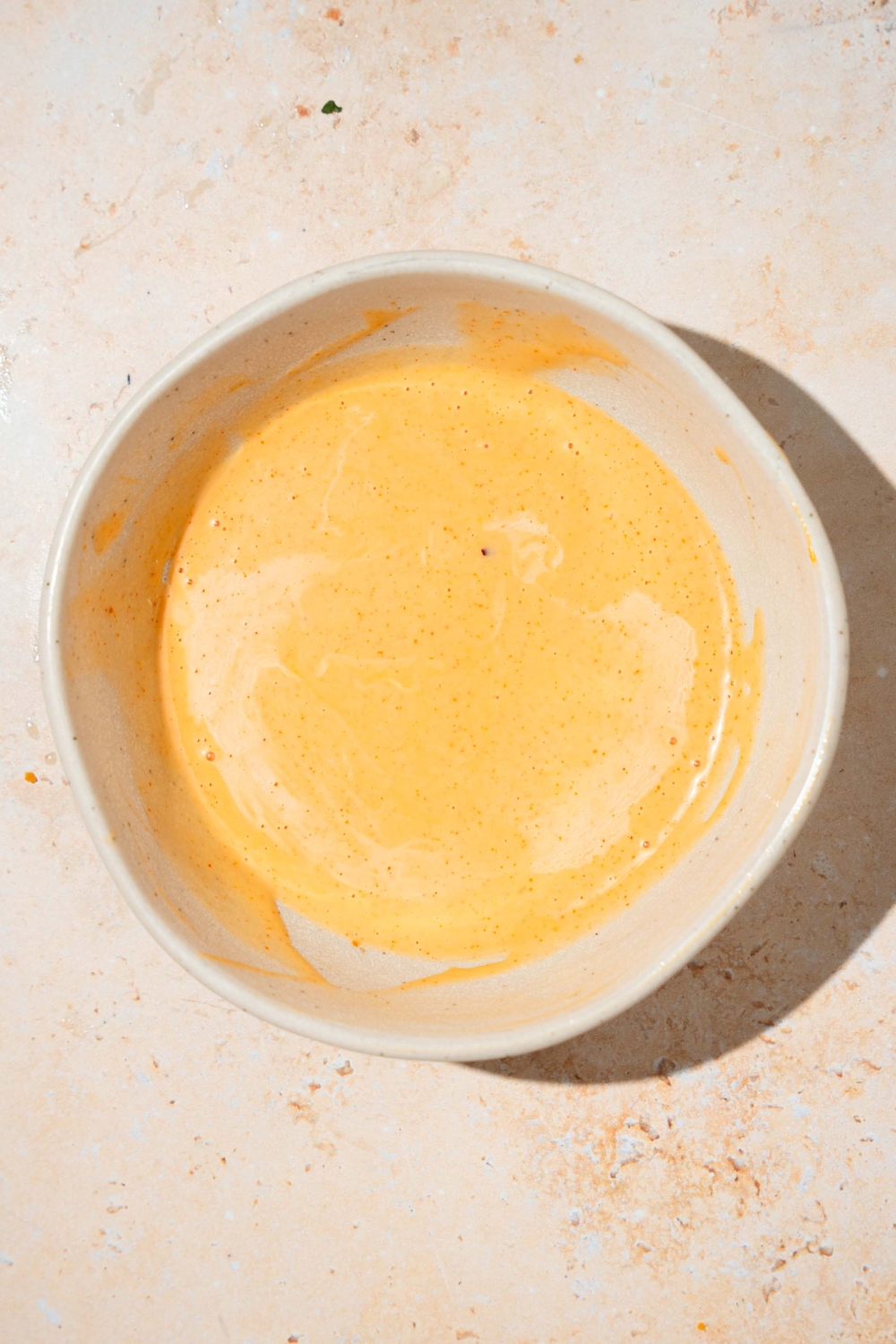 A bowl of mixed bang bang sauce. The bowl is on a tan counter.