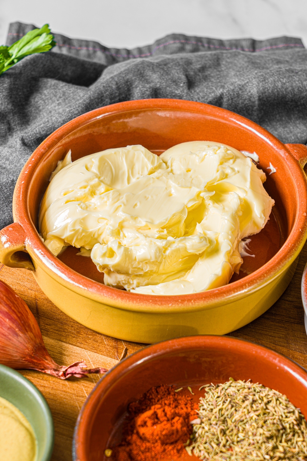 A small bowl of softened butter on a wooden board with additional bowls of ingredients.