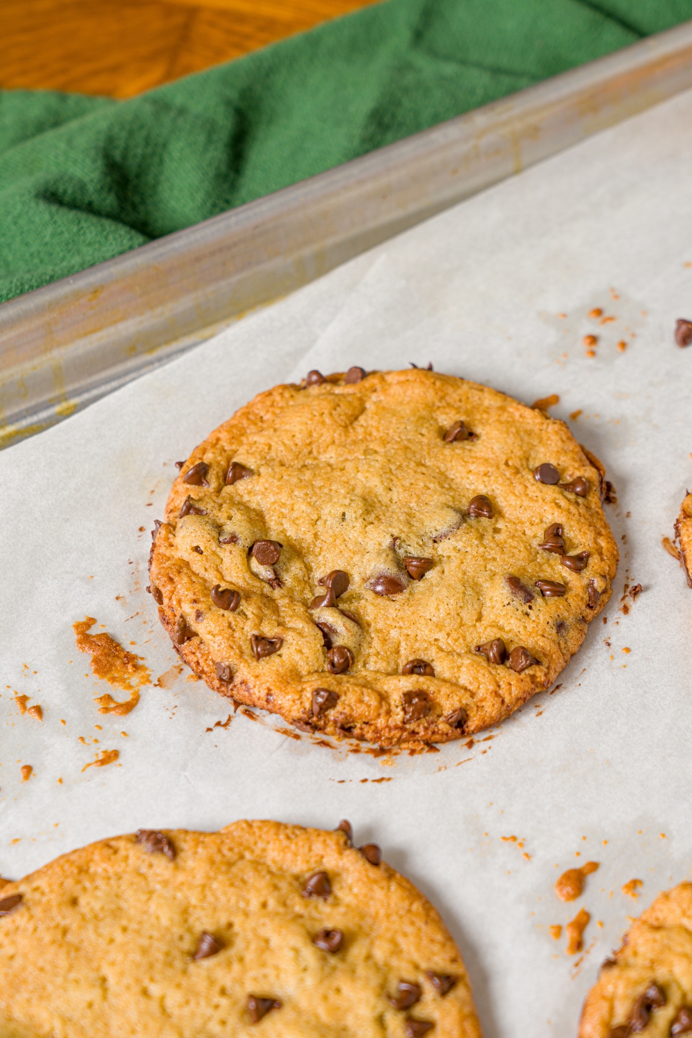 A baking sheet lined with parchment paper with baked chocolate chip cookies without baking soda.