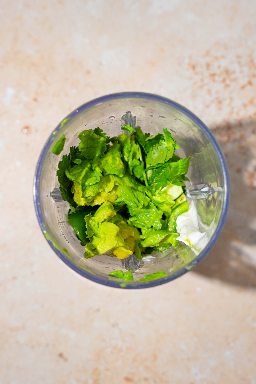 A blender with ingredients to make fish taco sauce including sour cream, cilantro, avocado, and more.