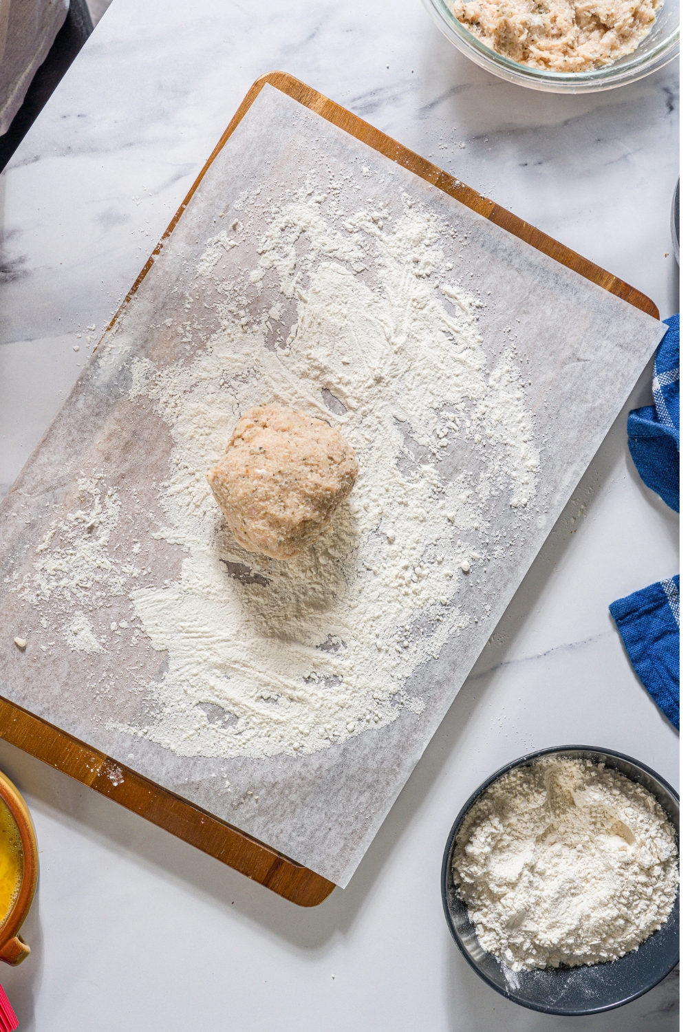 Ground chicken mixture on top of flour that is on a parchment line bacon sheet.