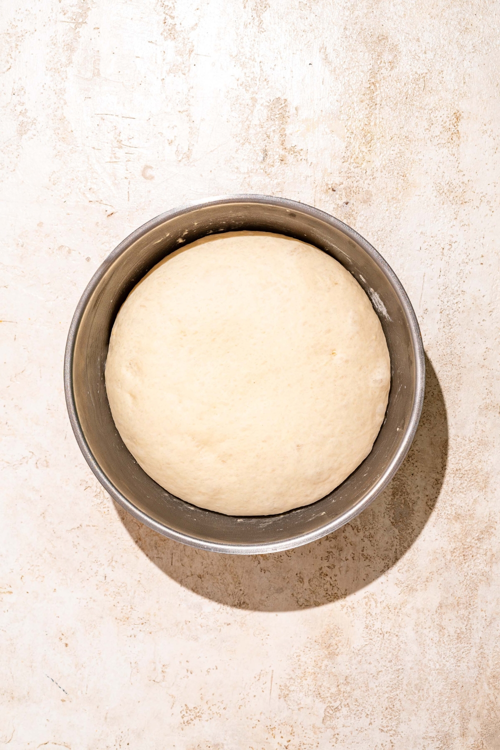 A large bowl with risen Dutch Crunch bread dough. The bowl is on a tan counter.
