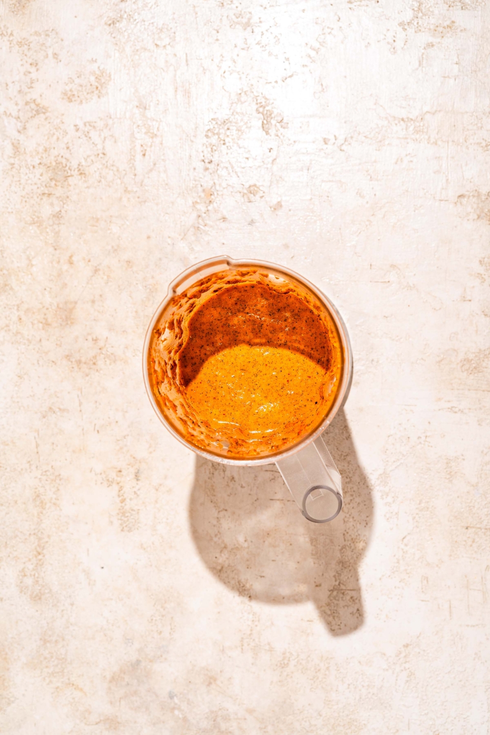 A blender jar with blended peri peri sauce. The jar is on a tan counter.