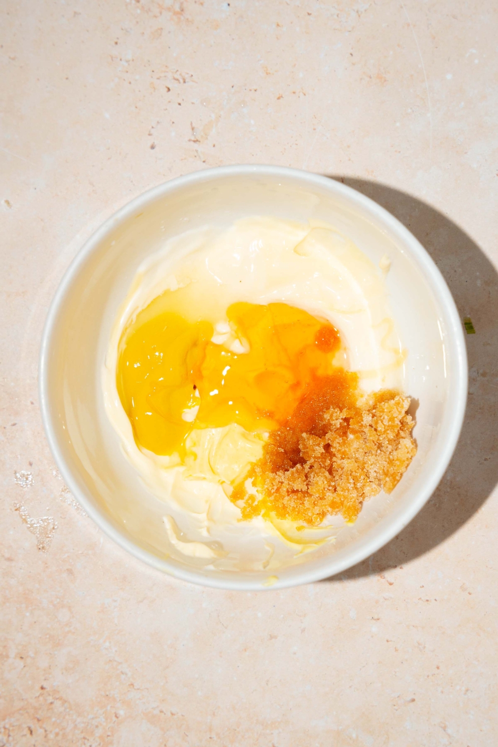 A bowl of ingredients to make honey mustard sauce including mayo, yellow mustard, dijon mustard, honey, and brown sugar.