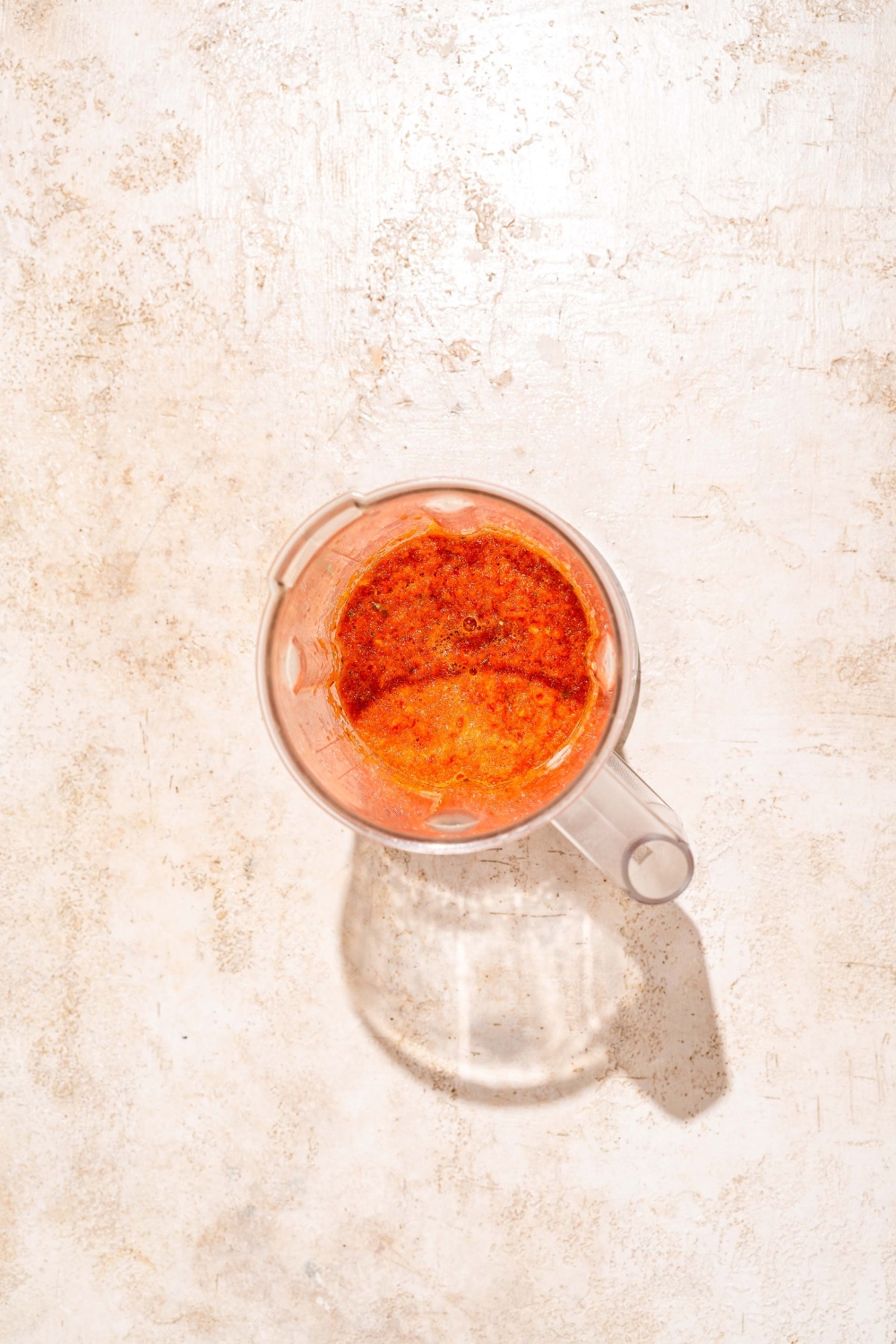 A blender with blended fresh ingredients for peri peri sauce. The jar is on a tan counter.