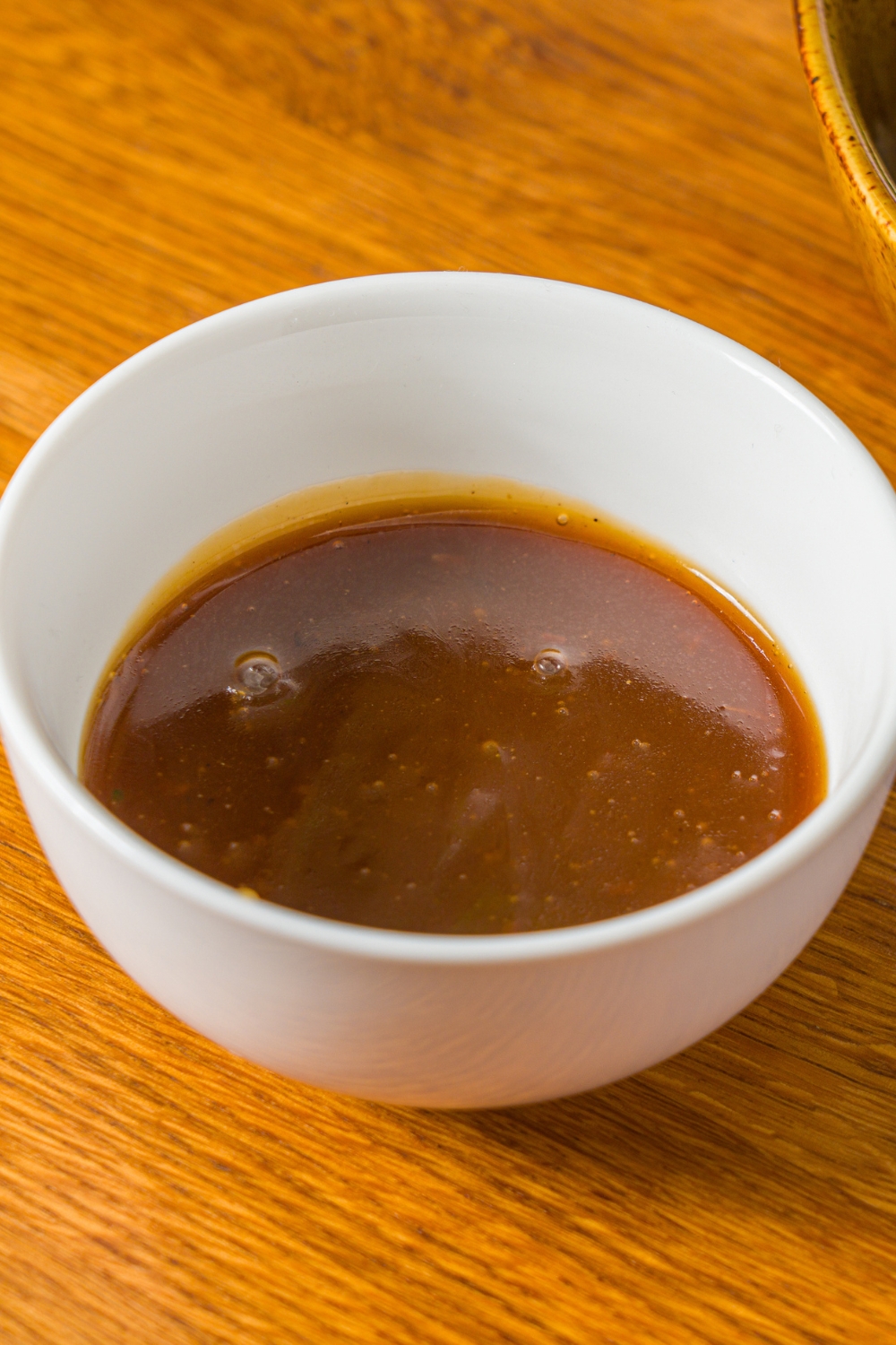 A small bowl of teriyaki sauce on a wooden counter.