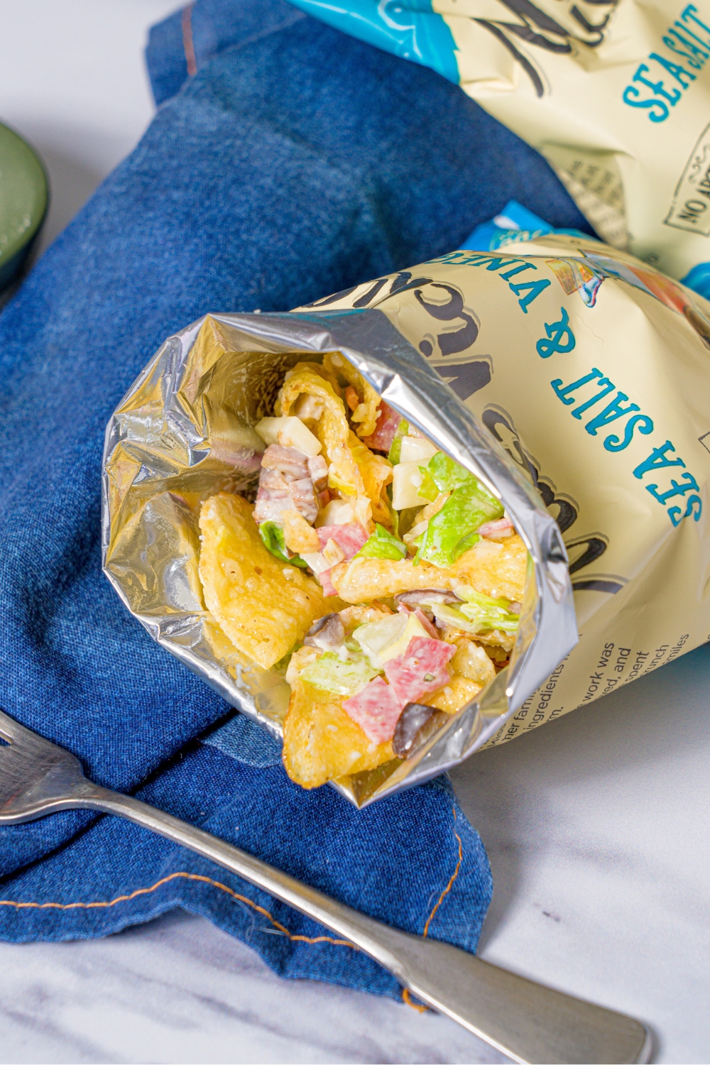 A bag of salt vinegar chips that has a chopped Italian sandwich, filling, and the salt and vinegar chips in it.