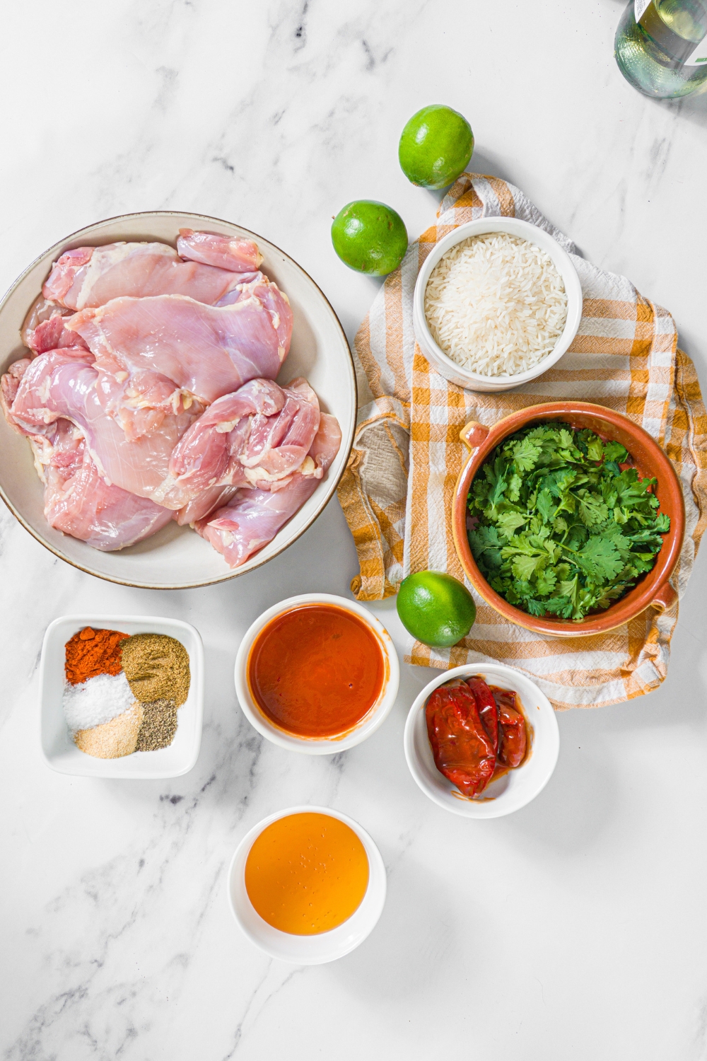 A bowl of chicken, a bowl of rice, a bowl of cilantro, a lime, a bowl of seasonings, a bowl of honey, a bowl of adobo.