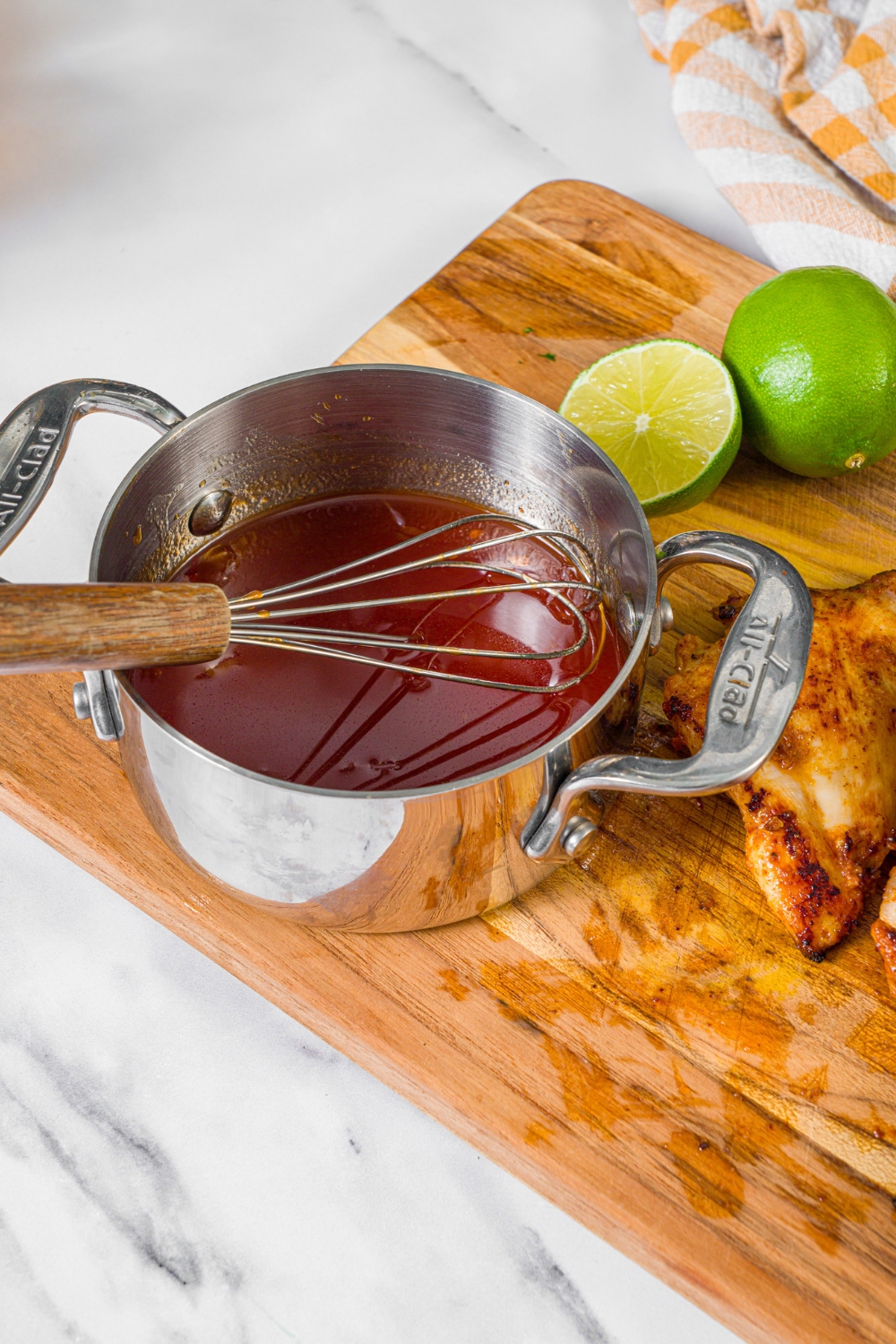 A pot with a whisk in it with chipotle honey sauce in it.