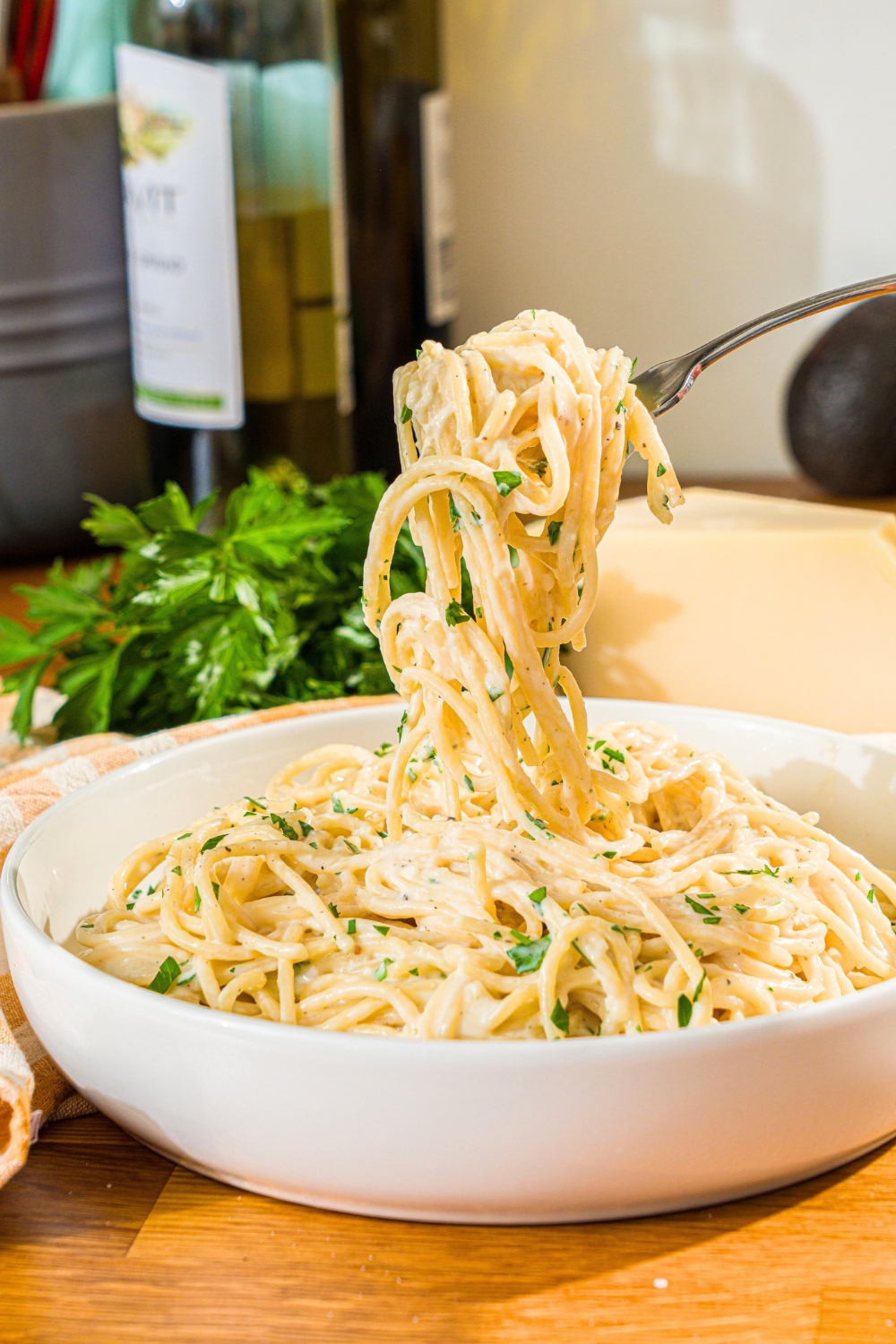 A fork twirled with creamy garlic parmesan pasta noodles being pulled from a bowl that is filled with the garlic parmesan pasta.